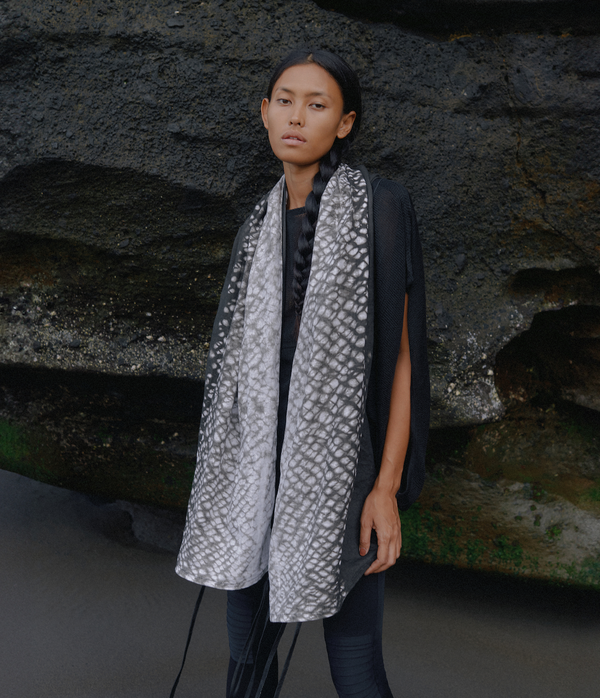 women standing in front of a black rock wearing a black and white tie dye linen scarf with leather tassels