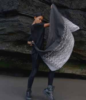 women standing in front of a black rock holding a black and white tie dye linen scarf