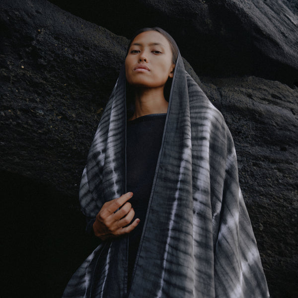 women standing in front of a black rock wearing a black and white tie dye linen shawl 