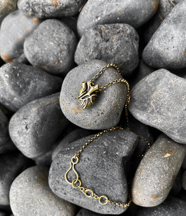 Gold necklace with a heart pendant on gray stones