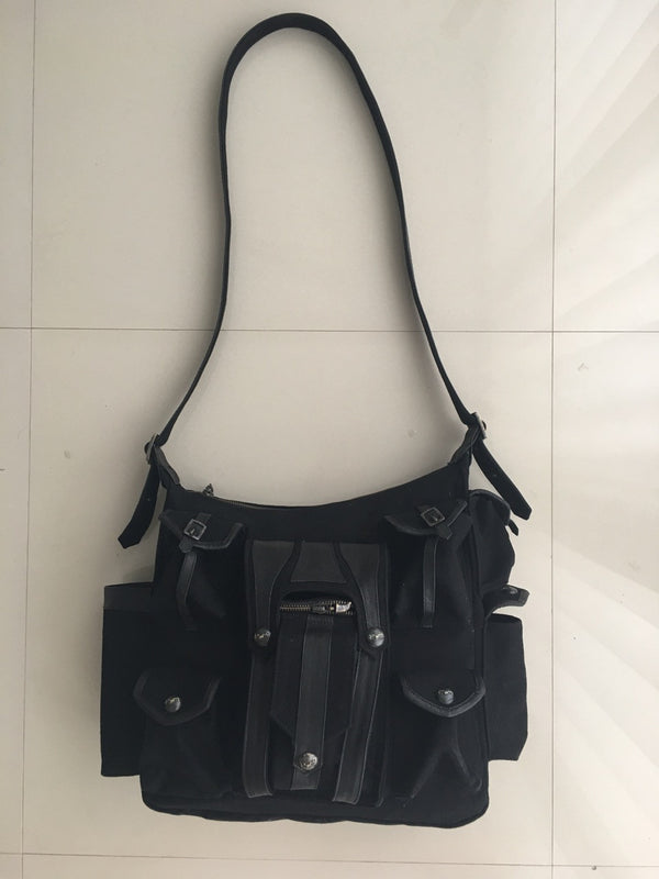 Canvas and leather shoulder travel bag with fabric lining and custom hardware.