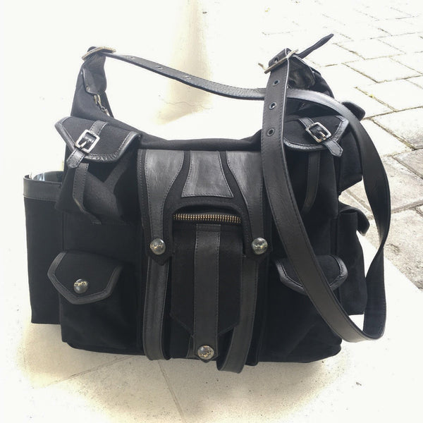 Canvas and leather shoulder travel bag with fabric lining and custom hardware.