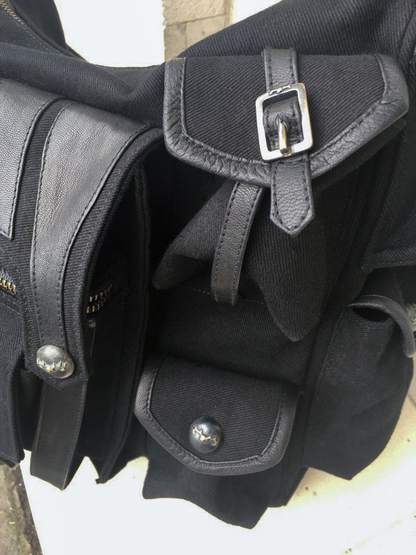 Canvas and leather shoulder travel bag with fabric lining and custom hardware.