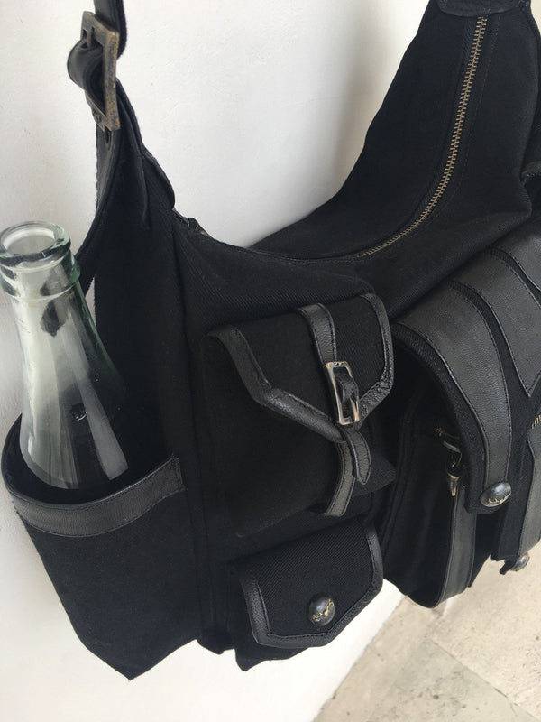 Canvas and leather shoulder travel bag with fabric lining and custom hardware.
